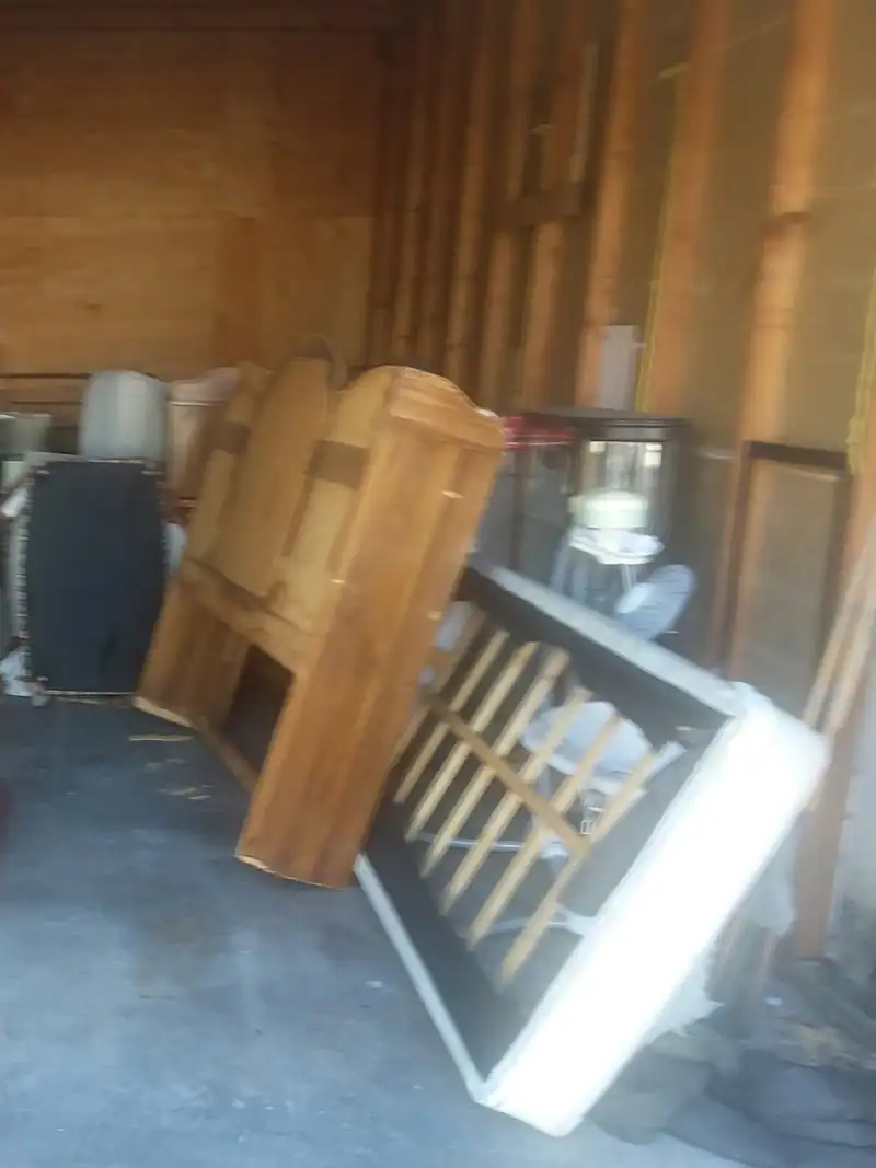 A storage unit full of old wood furniture, chairs and a cabinet